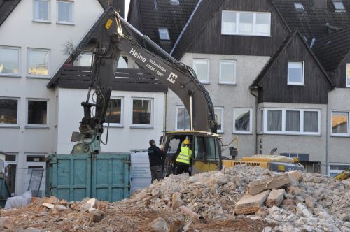 zwei Personen bei einem Bagger umgeben von Schutt