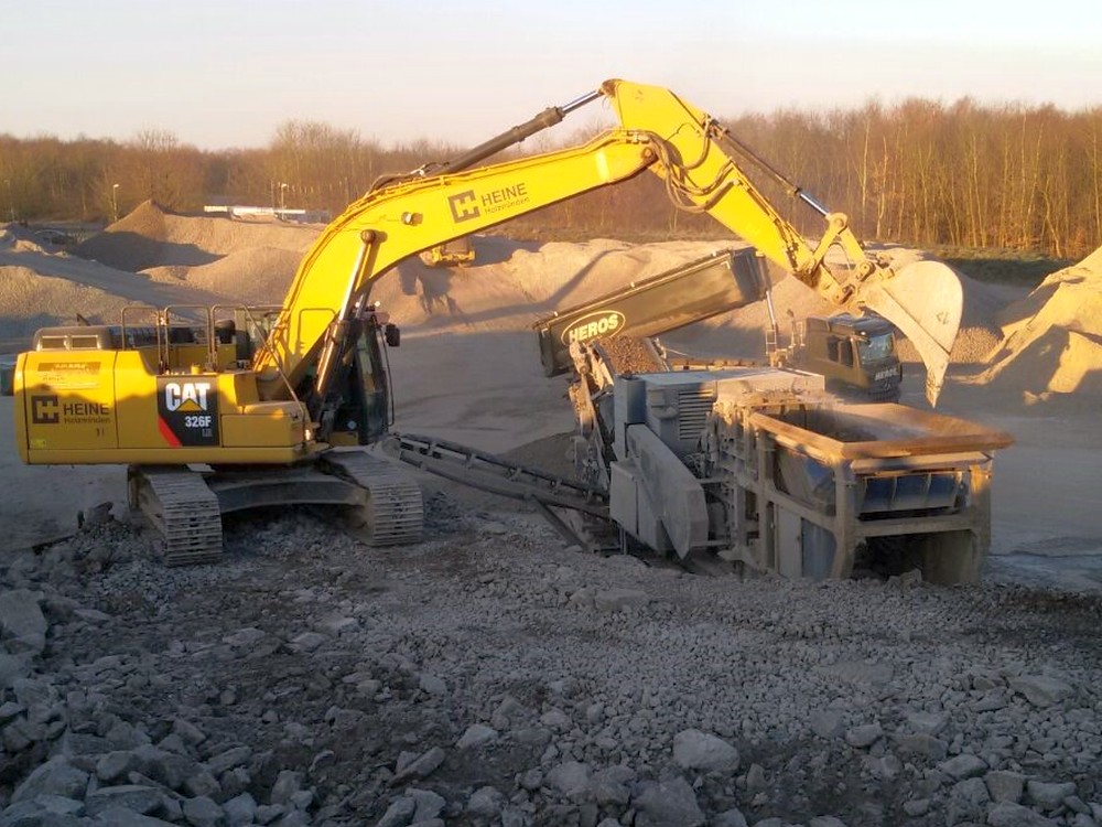 bagger steht mit seiner Schaufel vor einem Container